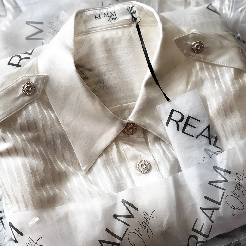 Realm Origin shirt packaged in branded tissue with tag and label, representing complimentary express shipping and premium customer presentation.