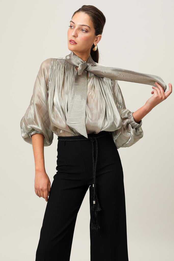 Editorial mood shot of the Realm Origin Atelier Bow Top in semi-sheer Japanese satin, showcasing adjustable bow tie neckline, voluminous sleeves and gathered bodice.