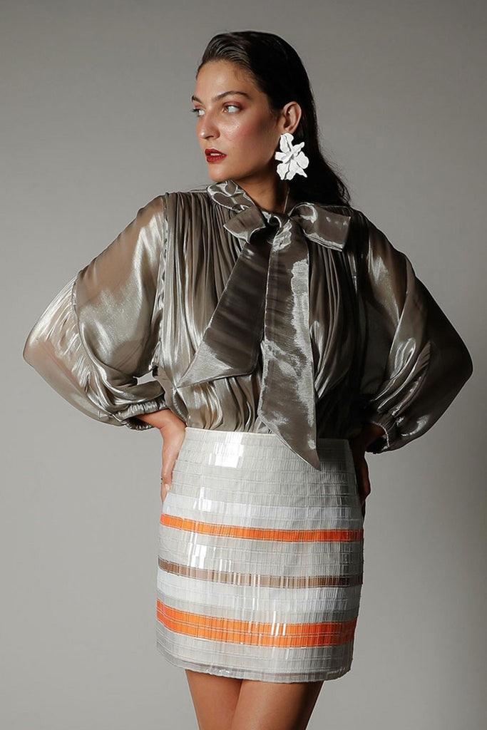 Editorial campaign shot of the Realm Origin Atelier Bow Top in semi-sheer satin with adjustable bow tie, 3/4 voluminous sleeves, shoulder panel piping and gathered front and back bodice