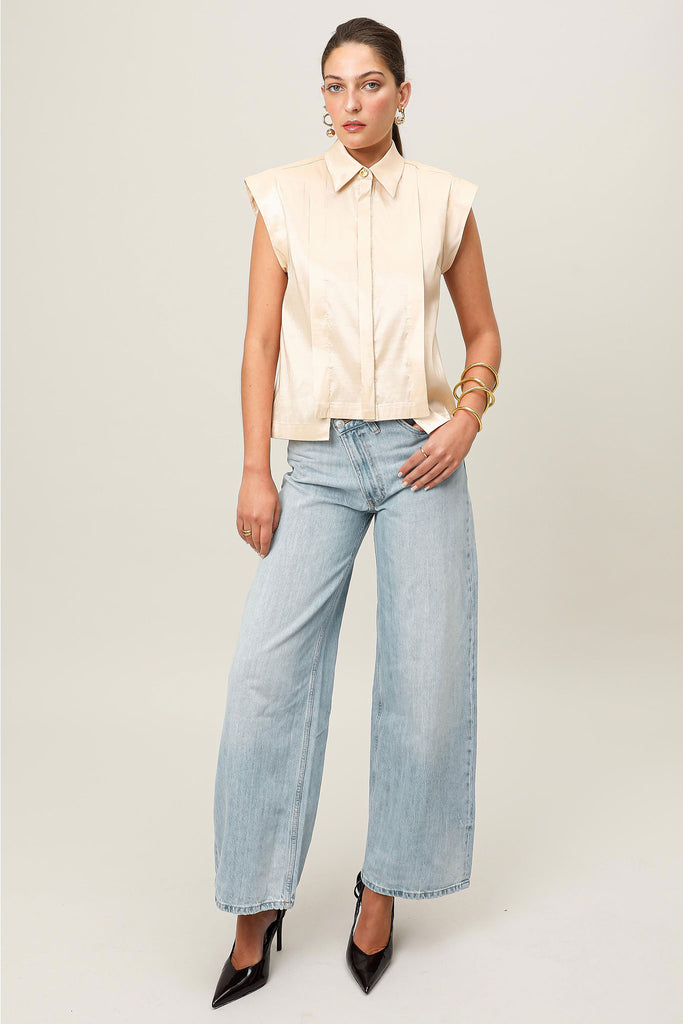 Front on-model e-commerce view of the Realm Origin Sol Verite Shirt in powder beige, structured sleeveless taffeta shirt with front flange pleats, shoulder pads and step hem.