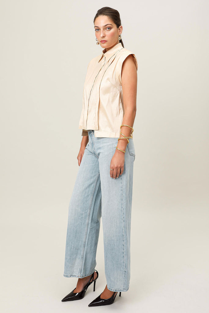 E-commerce side profile of the Realm Origin Sol Verite Shirt in powder beige taffeta, structured sleeveless shirt featuring front flange pleats, shoulder pads and step hem.